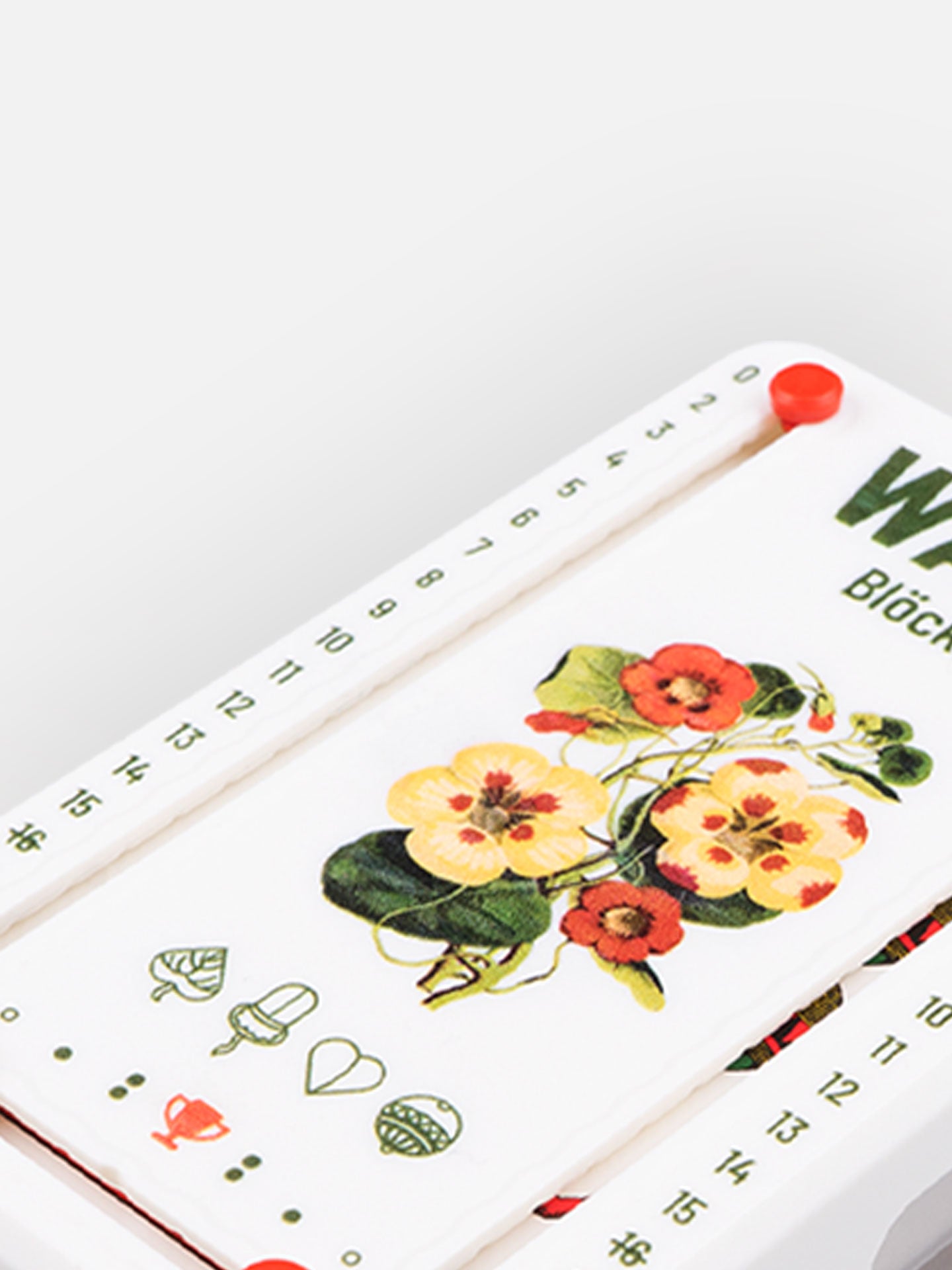 Detail Aufnahme Wattblöckl aus weißen Kunststoff mit Blütenblatt Motiv auf grauen Hintergrund.