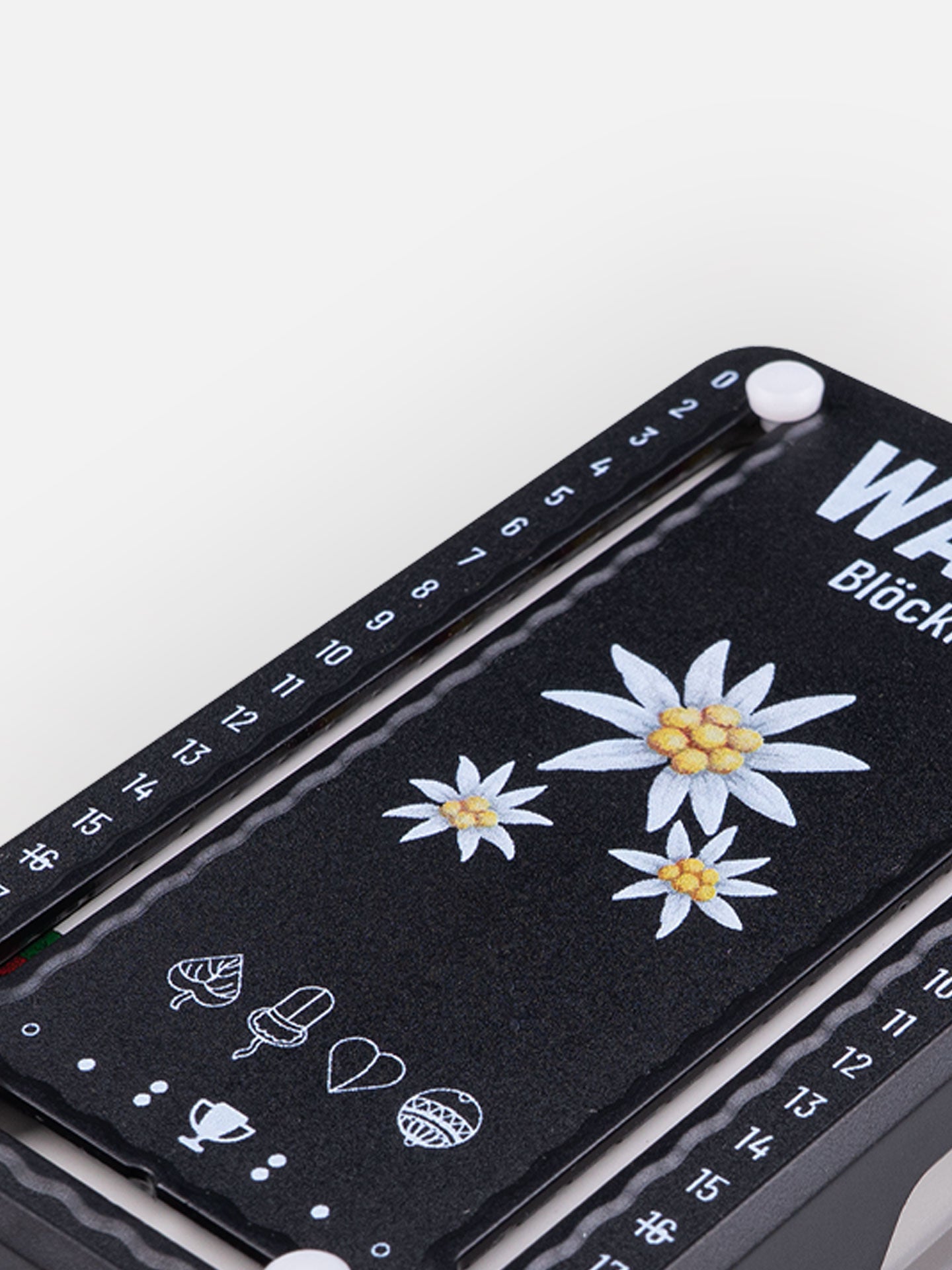 Detail Aufnahme Wattblöckl aus Kunststoff schwarz mit Edelweiß Motiv auf grauen Hintergrund.