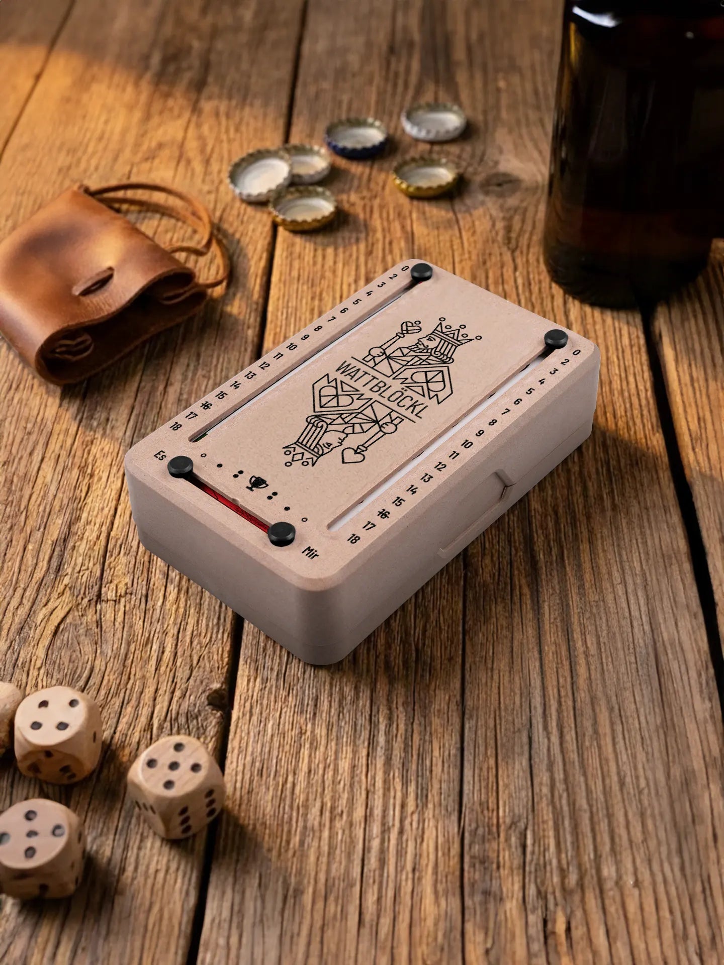 Wattblöckl in Holzoptik mit schwarzen Pins und KoenigKoenigin-Motiv. Platziert auf Holztisch mit Würfeln und Kronkorken.